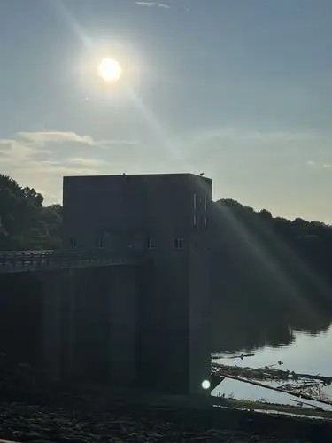 Sun-drenched concrete meets serene waters and green hills.